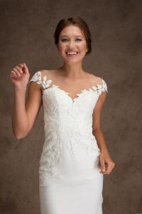 Bride wearing off-the-shoulder lace wedding dress with illusion neckline