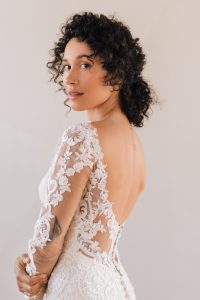 Close-up of a long sleeve lace wedding dress showcasing sheer floral sleeves, an open-back design, and detailed lace patterns for a sophisticated bridal finish.