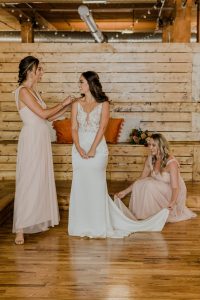 A bridge with her two bridesmaid. The bride is wearing a white Silk Satin wedding dress getting ready photo blush bridesmaid dress