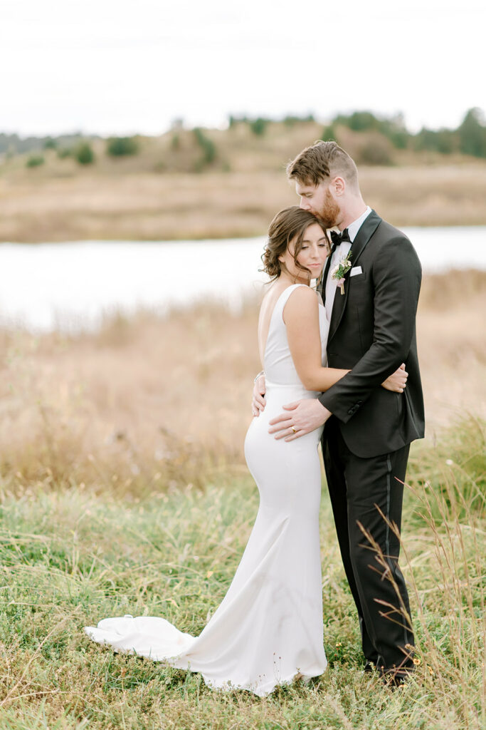 simple bridal gown crepe fitted dress deep v bride and groom in field