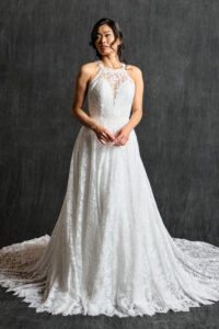 Front view of a halter neck lace wedding dress featuring a high neckline and delicate floral lace pattern, complemented by a flowing skirt and soft train, ideal for a modern yet timeless bridal look.