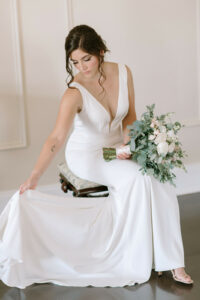 classic crepe bridal gown deep v neck romantic updo bride sitting with bouquets